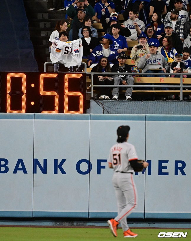 샌프란시스코 자이언츠 이정후가 3일 미국 로스엔젤레스 다저스타디움에서 열린 LA 다저스와 2024 MLB 방문경기 도중 외야에서 이정후의 키움 히어로즈 시절 유니폼을 들고 응원하는 팬들을 바라보고 있다.