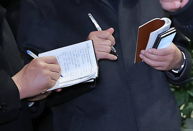 〈사진 3〉 왼쪽 사람의 수첩에는 비교적 자세한 문장이 쓰여 있다.