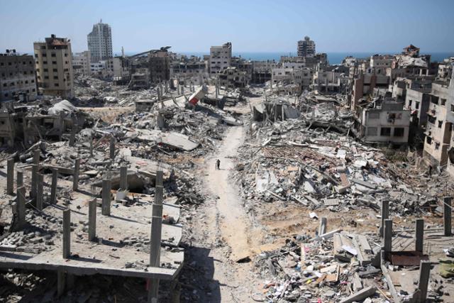 한 남성이 3일 이스라엘군 공습을 받은 가자지구 북부 가자시티의 알시파 병원 건물 잔해 사이로 자전거를 끌고 지나가고 있다. 가자시티=AFP 연합뉴스