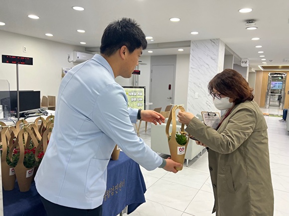 직원이 식목일을 맞아 내원객들에게 꽃화분을 나눠주고 있다.[사진=한국건강관리협회 대전충남지부