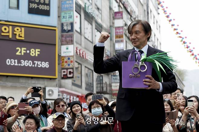 조국 조국혁신당 대표가 8일 경기 군포 산본로데오거리에서 열린 ‘검찰독재 조기종식, 군포시민과 함께’ 행사에서 한 지지자에게 받은 명품 가방과 대파를 상징하는 모형물을 들고 발언하고 있다. 문재원 기자