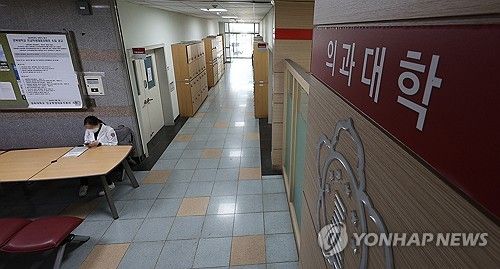 지난 8일 오전 비대면으로 수업을 재개한 대구 중구 경북대학교 의과대학에서 한 학생이 가운을 입고 복도에 앉아 있다.ⓒ연합뉴스