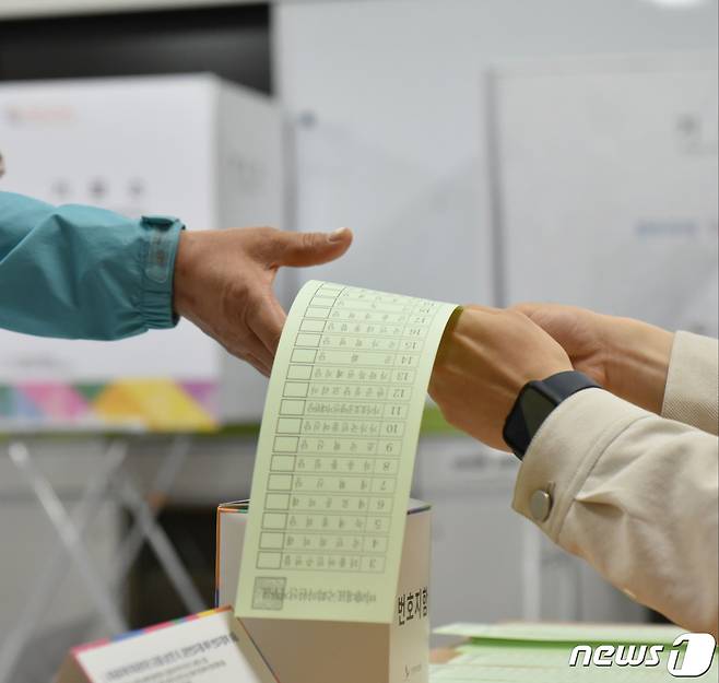 제22대 국회의원 선거 본투표 당일인 10일 오전 전남 광양시 광양읍 제4투표소(광양동초등학교)에서 한 유권자가 투표용지를 건네받고 있다.2024.4.10/뉴스1 ⓒ News1 김동수 기자