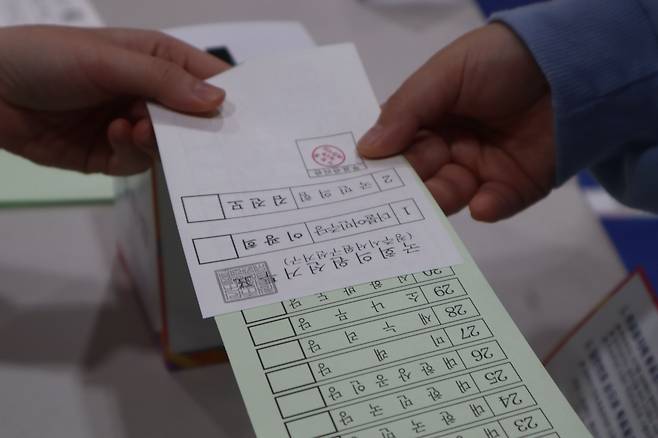 유권자들이 투표용지를 건네받고 있다. /뉴스1