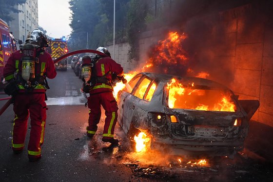 지난해 프랑스에서 열린 시위로 불이 붙은 차에 불을 끄는 소방관들 모습. AFP=연합뉴스