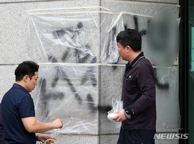 [서울=뉴시스] 김명년 기자 = 11일 오후 서울 서초동 서울고등검찰청 건물에 문재인 전 대통령과 서훈 전 국가정보원장을 비방하는 내용의 낙서를 하고 건물 창문에 돌을 던진 40대 남성이 경찰에 붙잡혔다. 사건 현장에서 청사 관계자들이 비닐막으로 낙서를 가리고 있다. 2024.04.11. kmn@newsis.com