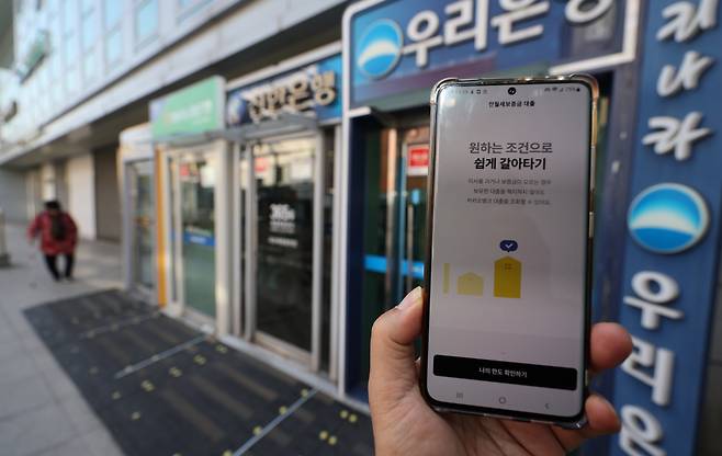 휴대전화 뱅킹앱과 서울 시내 거리의 은행 현금자동입출금기. [연합]
