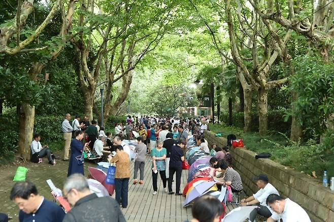 상하이 인민공원 ‘맞선코너(相亲角)’ 에서 전단지를 살펴보는 사람들.  중국에서는 머리가 하얀 부모들이 자식들을 대신해 맞선을 본다고 해서 ‘백발상친각(白髮相親角)’이라는 말도 쓰인다. [바이두]
