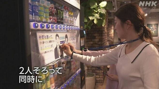 직원 2명이 화제의 자판기에 각각 사원증을 동시에 찍고 있는 모습.