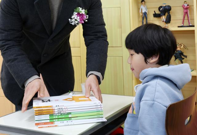 지난달 4일 강원 태백시의 한 초등학교에서 열린 2024학년도 입학식에서 1학년 신입생이 담임 교사로부터 교과서를 받고 있다. 연합뉴스