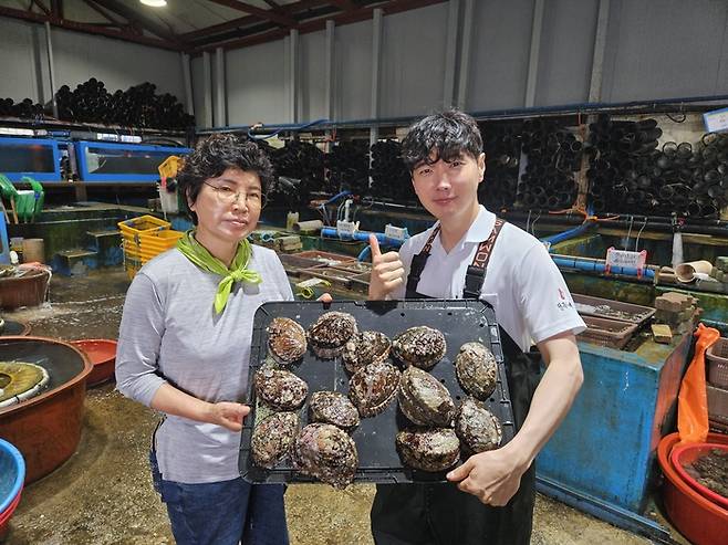 유장영 대표(오른쪽)와 그의 모친이 전복을 들고 사진을 찍고 있다.