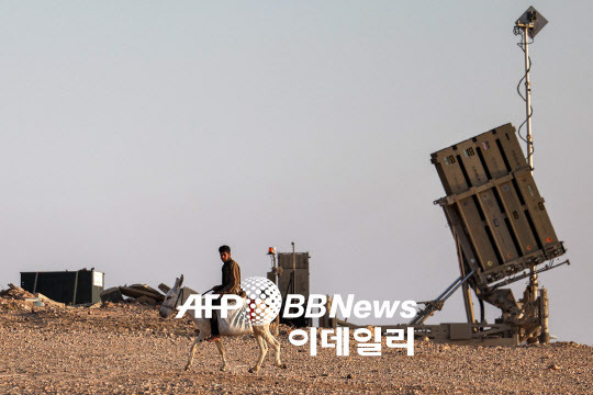 이스라엘 아이언돔 미사일 방어 시스템 포대 옆을 나귀를 탄 사람이 지나가고 있다(사진=AFP)