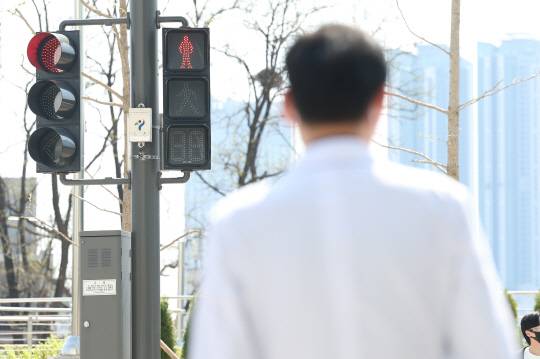 전공의 집단행동이 이어지고 있는 9일 오전 서울 시내 한 대형병원에서 한 의료 관계자가 횡단보도 신호를 기다리고 있다.   [연합뉴스]