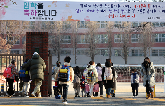Elementary school students enter a school compound in downtown Seoul last month. [NEWS1]