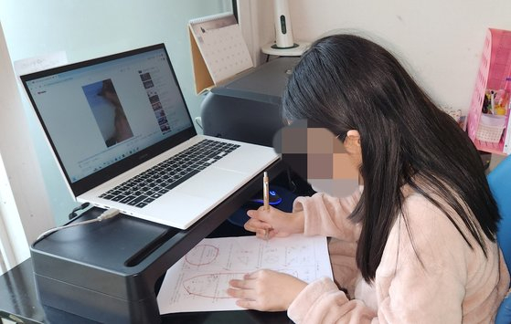 A 13-year-old girl studies by herself at her home in Yongin, Gyeonggi, after dropping out of elementary school. [JOONGANG PHOTO]