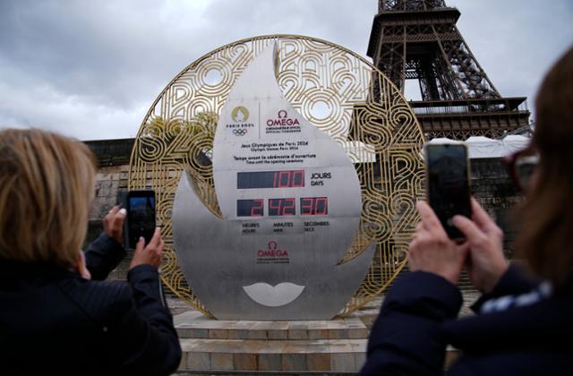 17일 프랑스 파리 에펠탑 앞에 설치된 파리하계올림픽 개최 카운트다운 시계를 관광객들이 촬영하고 있다. 파리=AP 연합뉴스
