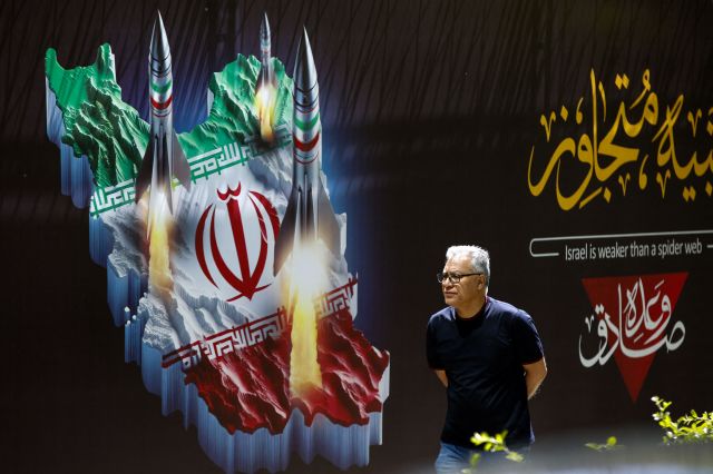한 남성이 19일(현지시간) 미사일이 그려져 있는 이란 테헤란 시내를 따라 걷고 있다. 이날 이란 이스파한 주에 폭발음이 들리는 등 이스라엘이 이란에 대한 재보복 공격을 감행했다. AFP연합뉴스