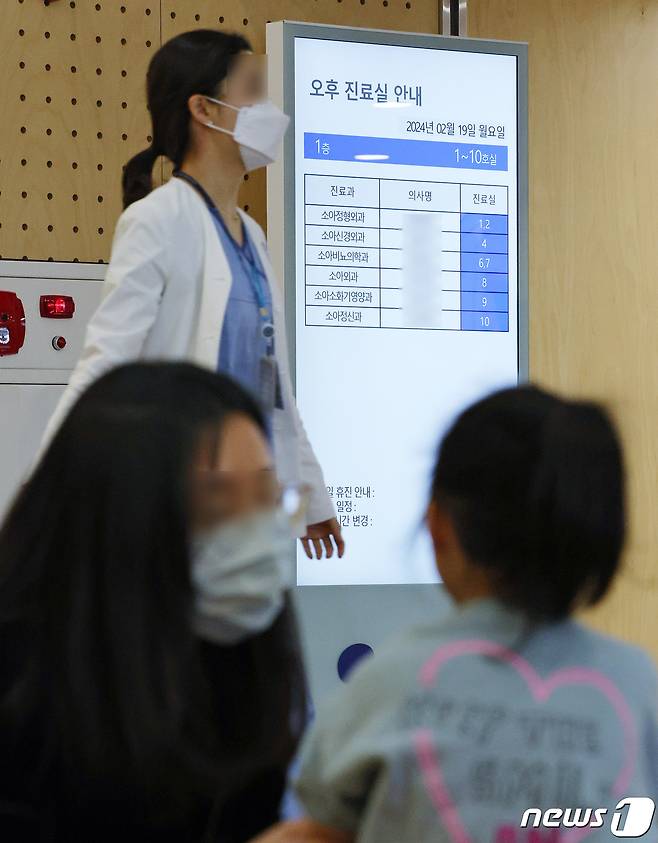 서울의 한 어린이병원에서 진료를 기다리는 어린이 가족 뒤로 의료진이 지나가고 있다.  2024.2.19/뉴스1 ⓒ News1 장수영 기자
