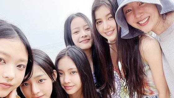 '어텐션' 뮤직 비디오 촬영이 진행된 스페인의 한 해변에서 뉴진스 멤버와 민희진 대표가 기념 사진을 찍고 있다. 왼쪽부터 해린, 민지, 혜인, 하니, 다니엘, 민 대표. 사진 민희진
