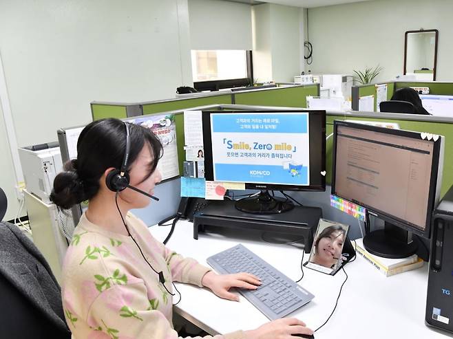 한국조폐공사 콜센터 상담직원이 거울을 보며 밝게 웃는 모습으로 고객과 통화하고 있다. 한국조폐공사 제공