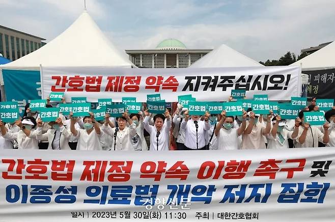 Members of the Korea Nursing Association shout slogans in front of the National Assembly in Yeongdeungpo-gu, Seoul, May 30, 2023, calling for the fulfillment of promises to enact a nursing bill. By Taehyung Cho