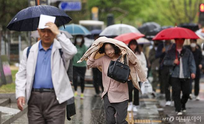 서울 종로구 세종대로에서 한 시민이 옷으로 머리를 가린 채 이동하고 있다./사진=뉴시스