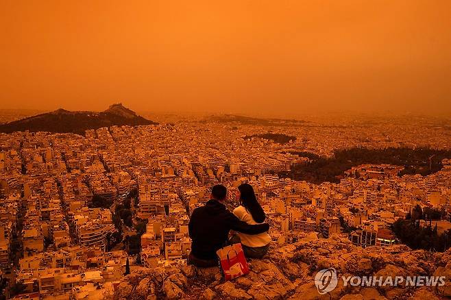 그리스 아테네 뒤덮은 모래폭풍 (아테네 AFP=연합뉴스) 23일(현지시간) 그리스 아테네의 투르코부니아 언덕에 한 커플이 앉아 주황빛으로 변한 도시 풍경을 바라보고 있다. 2024.04.23 photo@yna.co.kr