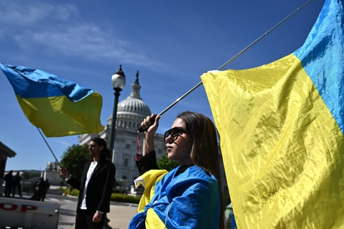 23일(현지시간) 미국 워싱턴 연방의회 의사당 앞에서 우크라이나 지원을 촉구하는 시민들이 우크라이나 국기를 몸에 두르고 시위를 벌이고 있다. AFP연합뉴스