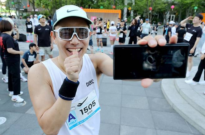 서울 하프마라톤 참가한 정영준(44)씨가 28일 오전 출발지인 서울 광화문 광장에서 초음파 사진을 들고 활짝 웃고 있다. 정씨는 "달리기 덕에 10년 만에 아이가 찾아왔다"고 했다. / 오종찬 기자