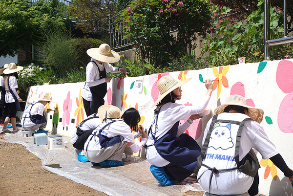 기독삼애원 운동장 한 켠에 꽃을 그리고 있는 아이엠아이 직원들. 사진제공 = 아이엠아이