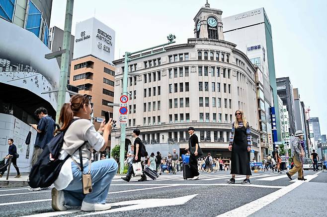 29일(현지 시각) 한 여성이 도쿄 긴자 쇼핑가의 주요 교차로에서 사진을 위해 포즈를 취하고 있다. / AFP 연합뉴스