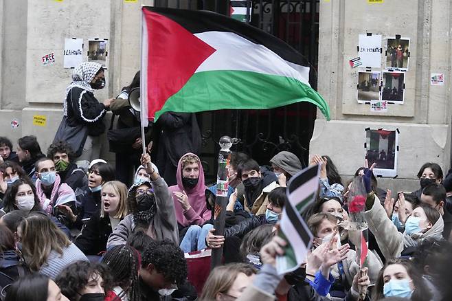 지난달 26일(현지 시간) 프랑스 파리 시앙스포(파리정치대) 인근에서 한 학생이 대형 팔레스타인 국기를 들고 있다. 시앙스포, 
소르본대 등 프랑스 주요 대학에서는 이스라엘의 팔레스타인 민간인 공격을 비판하는 학생들의 시위가 잦아들지 않고 있다. 파리=AP 
뉴시스