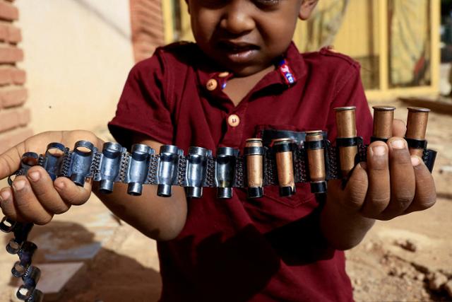 지난 14일 수단 수도 하르툼 북부에서 한 아이가 총탄을 들어 보이고 있다. 하르툼=로이터 연합뉴스