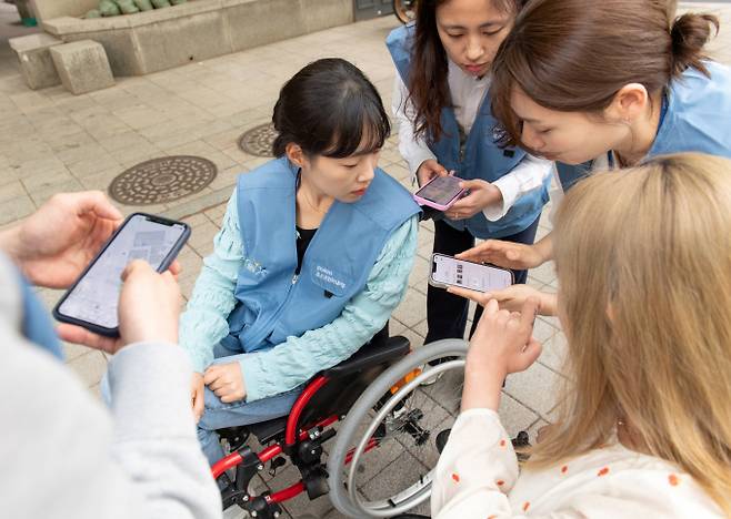 포스코인터내셔널 임직원들이 휠체어를 타고 다니며 휠체어 사용자 입장을 직접 경험하고 휠비(휠체어 전용 네비게이션) 앱에 들어갈 위치 정보를 수집하고 있다. /사진=포스코인터내셔널