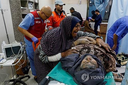 이스라엘 공격으로 부상당한 남편을 부둥켜안고 있는 팔레스타인 여성. [로이터=연합뉴스 자료사진. 재판매 및 DB금지]