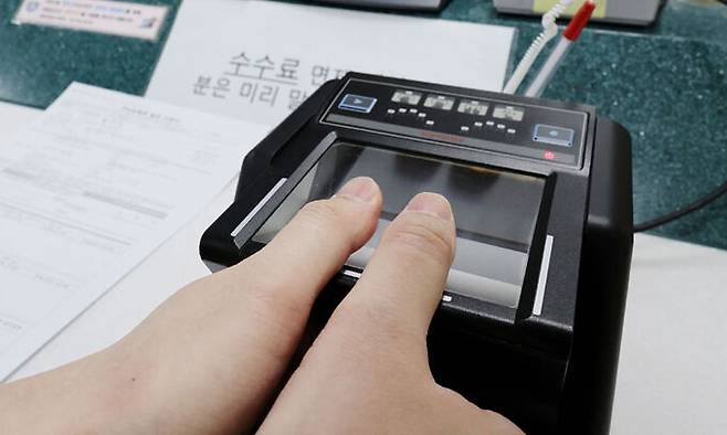 서울의 한 주민센터에서 시민이 주민등록증 발급을 위한 지문을 스캔하고 있다. 연합뉴스