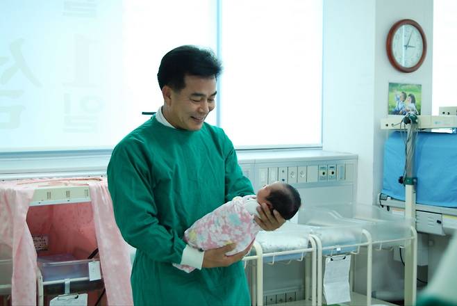 하충식 한마음국제의료재단의장이 2009년 5월 본인이 분만을 받은 신생아를 앉고 웃고 있다./창원한마음병원 제공
