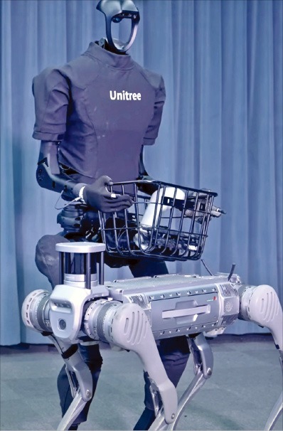 < 로봇개 심부름 ‘척척’ > 유니트리의 휴머노이드 ‘H1’이 로봇개가 가져온 물건을 전달받고 있다.  /유니트리 제공