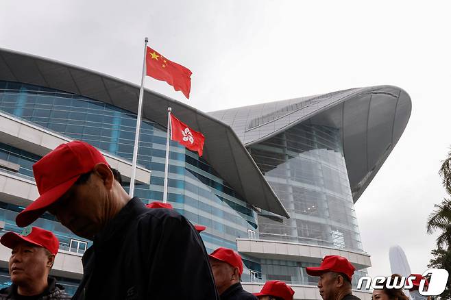 지난 3월 13일 홍콩의 컨벤션 및 전시센터 밖에서 중국 관광객들이 중국과 홍콩 국기 앞을 지나가고 있다. 2024.03.18 ⓒ 로이터=뉴스1 ⓒ News1 조소영 기자