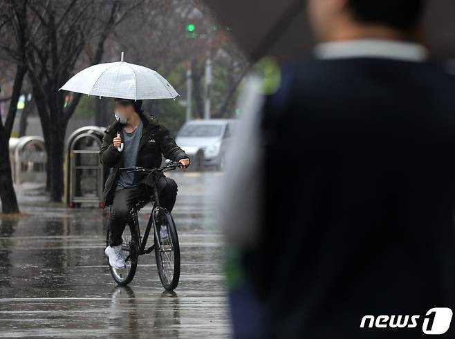 부산 해운대구 벡스코 인근에서 한 시민이 우산을 든 채 자전거를 타고 있다. 2023.12.11/뉴스1 ⓒ News1 윤일지 기자