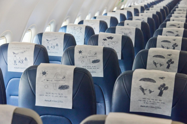 6명의 환아가 꿈꾸는 ‘가족 여행’ 그림이 에어로케이항공 기내 헤드레스트 커버에 그려진 모습. [사진출처=에어로케이항공]