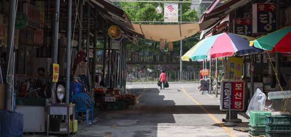 2024년 12월 폐지를 앞두고 있는 안산시 단원구 안산시민시장의 모습. 한 할머니가 시장에서 산 짐을 양손에 든 채 나서고 있다.