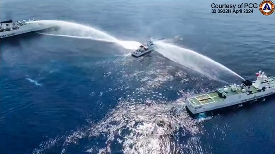 필리핀 해안경비대가 4월 30일 공개한 사진에서 필리핀 해안경비대 선박(가운데)이 남중국해 스카버러 암초 인근에서 중국 해경 선박 2척에 포위된 채 물대포를 맞고 있다. AFP=연합뉴스