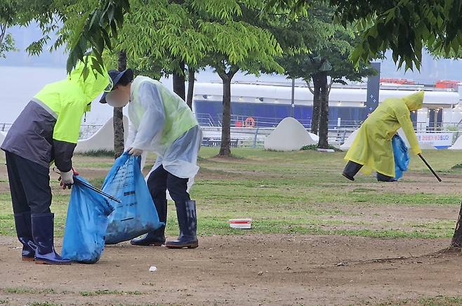 5일 오전 서울 여의도 한강공원에서 환경미화원들이 비가 오는 궂은 날씨에도 시민들이 버리고 간 쓰레기 등을 주우며 청소를 하고 있다. 사진=김경호 기자