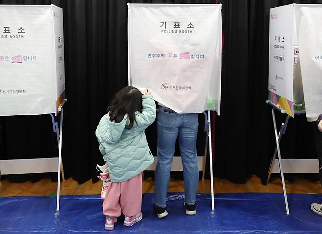 4·10 총선 사전투표가 시작된 지난달 5일 오전 서울 동작구 상도1동주민센터에서 한 어린이가 엄마가 투표하고 있는 기표소 커튼을 들춰보고 있다. 연합뉴스