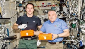 국제우주정거장(ISS) 내에서 단백질 결정 연구 장치를 들고 포즈를 취한 우주 비행사들.  NASA 제공