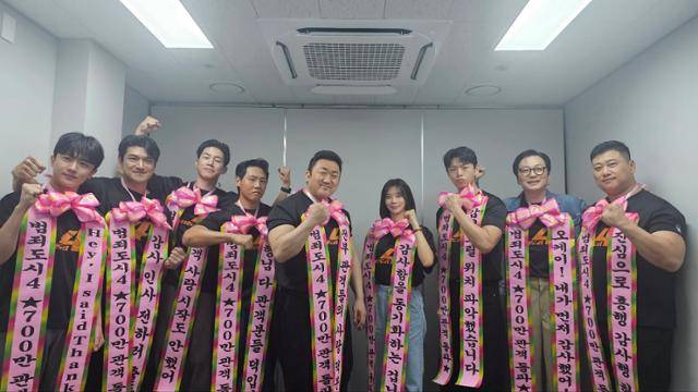 '범죄도시4' 허명행(맨 오른쪽) 감독과 출연 배우들이 화환 장식으로 지난 4일 관객 700만 명 돌파를 자축하고 있다. 에이비오엔터테인먼트 제공