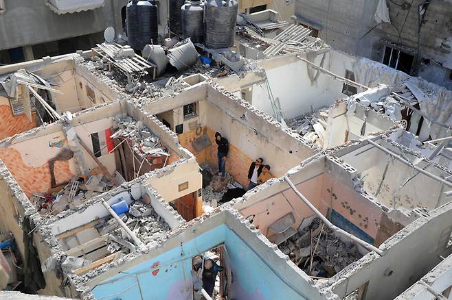 7일(현지시간) 가자지구 최남단 도시 라파에서 피란민들이 이스라엘 공습으로 파괴된 건물의 잔해를 살펴보고 있다. 신화연합뉴스