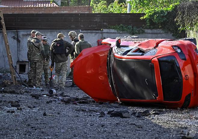 8일(현지시간) 우크라이나 자포리자에서 군경들이 러시아의 공격으로 뒤집어진 차를 바라보고 있다. 2024.05.08/ ⓒ 로이터=뉴스1 ⓒ News1 권진영 기자
