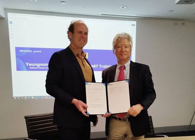 RMIT 제이크 하인리히 CEO(왼쪽)와 영남대 SW중심대학사업단 박용완 단장이 업무협약을 맺은 뒤  협약서를 들어보이고 있다.